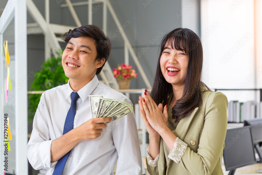Smiling man giving money laughing woman in office Smiling man giving money laughing woman in office