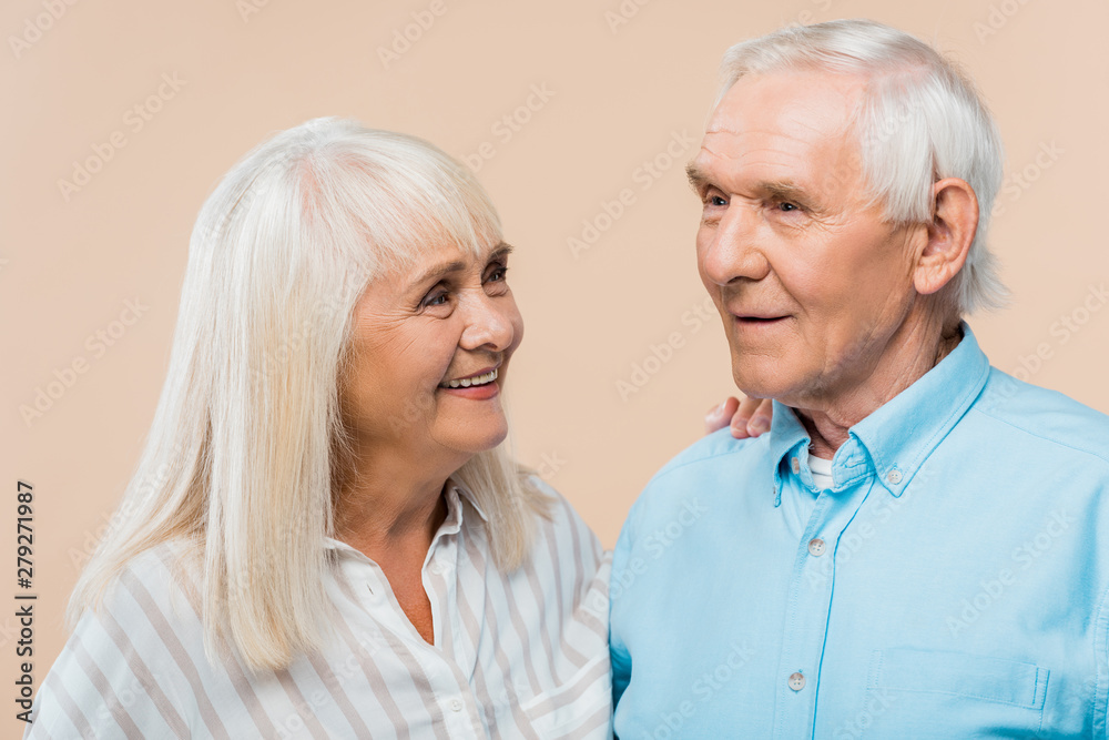 happy retired woman looking at man with grey hair isolated on beige happy retired woman looking at man with grey hair isolated on beige