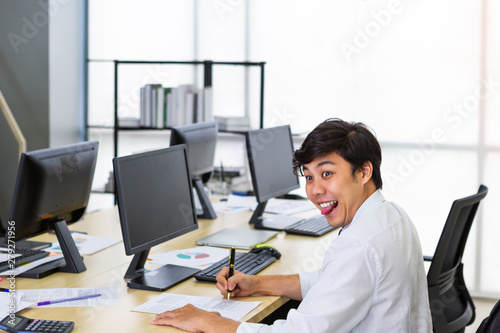 Asian man sticking out tongue during working in office
