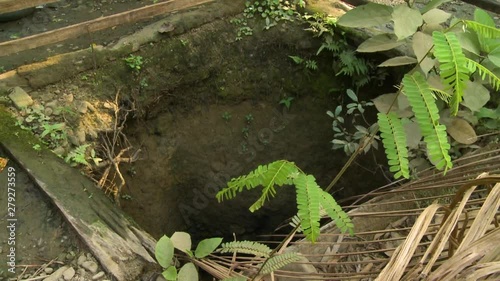 Close-up, low-angle panning shot of an open old dug-out pit at a village home, Myanmar