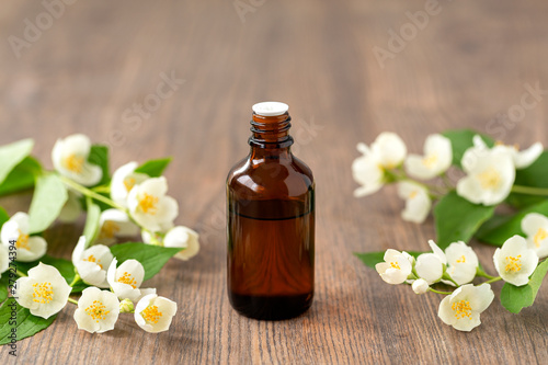 Essential aroma oil with jasmine on wooden background. Massage oil with jasmine flowers. Selective focus. 