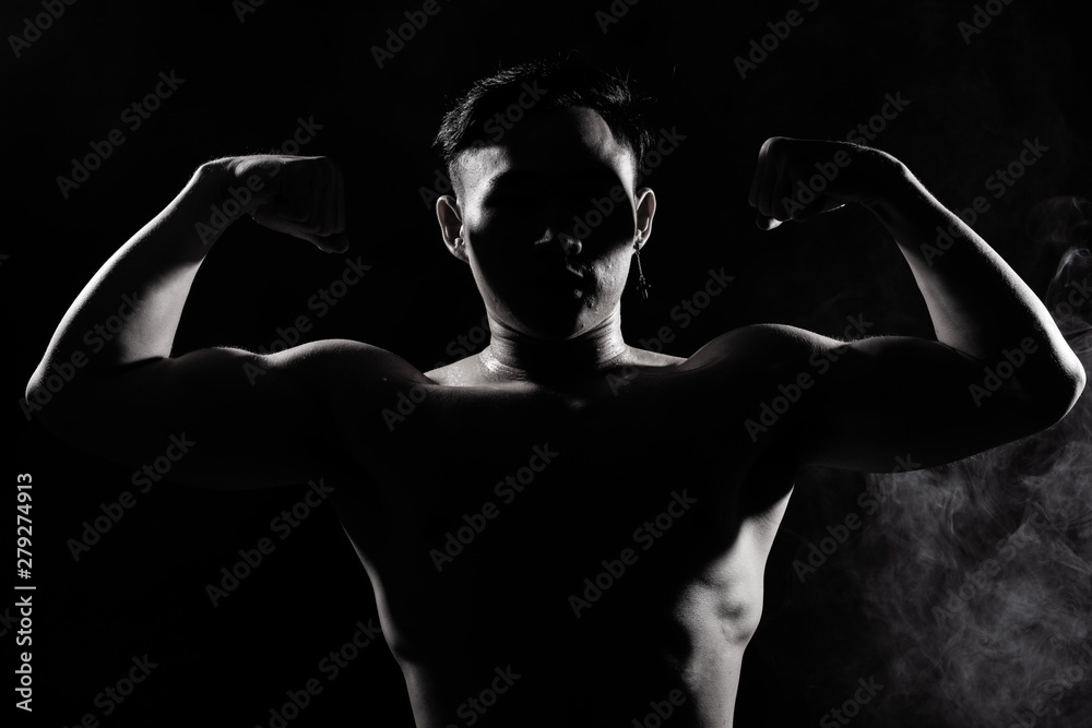 Asian Big Muscle Fitness Man exercise show arms, bicep, chest with sweat from heat. Young Sport Male six packs shoot in low key lighting exposure with shadow contrast, copy space Asian Big Muscle Fitness Man exercise show arms, bicep, chest with sweat from heat. Young Sport Male six packs shoot in low key lighting exposure with shadow contrast, copy space