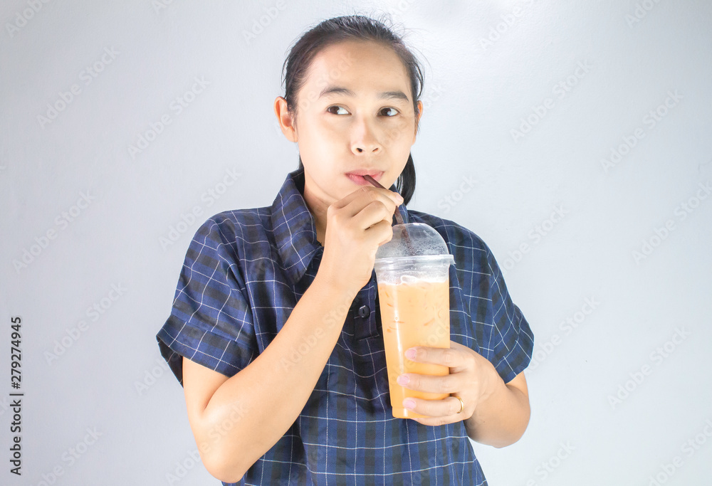 Happy Asian young woman is drinking Thai tea with milk. Popular beverage in Asia. Happy Asian young woman is drinking Thai tea with milk. Popular beverage in Asia.
