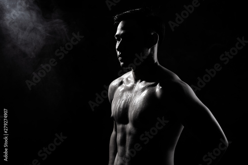 Asian Big Muscle Fitness Man exercise show arms, bicep, chest with sweat from heat. Young Sport Male six packs shoot in low key lighting exposure with shadow contrast, copy space