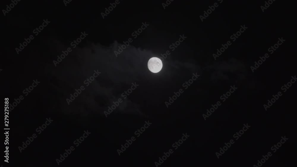 beautiful moon surrounded by clouds floating swiftly through the night sky.