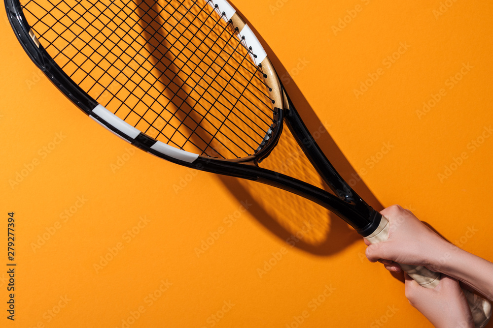cropped view of sportive woman holding tennis racket on yellow