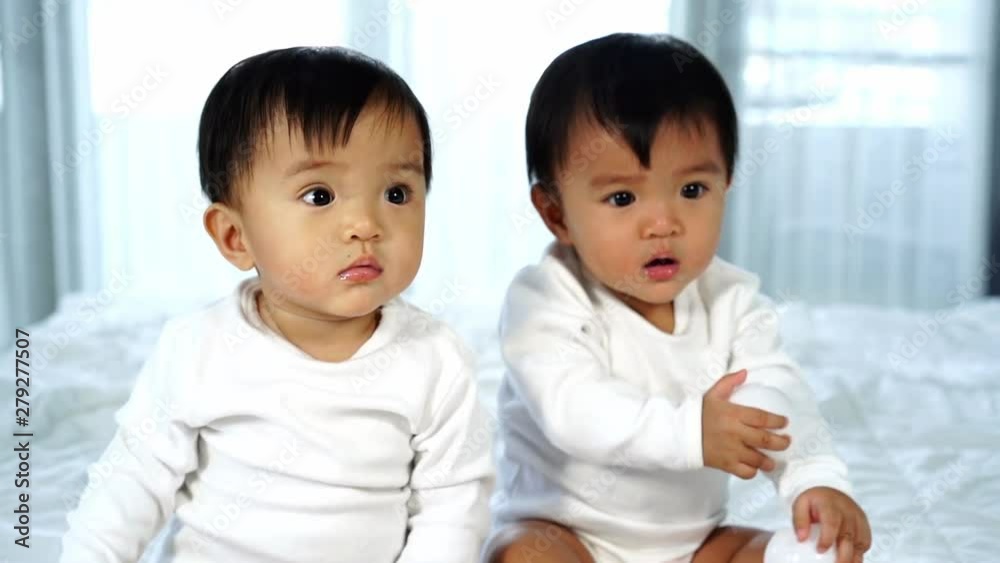 slow-motion of cheerful twin babies playing color ball on a bed slow-motion of cheerful twin babies playing color ball on a bed