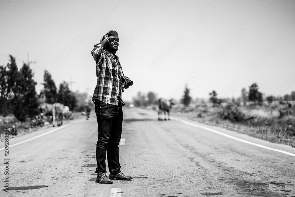African man photographer traveling in countryside with cows.B&W style