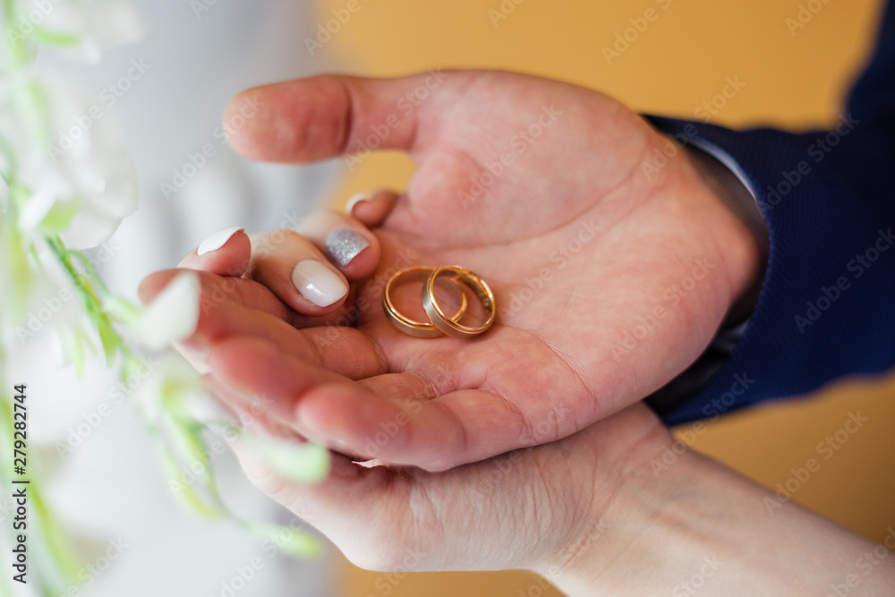 wedding rings in hands of newlyweds