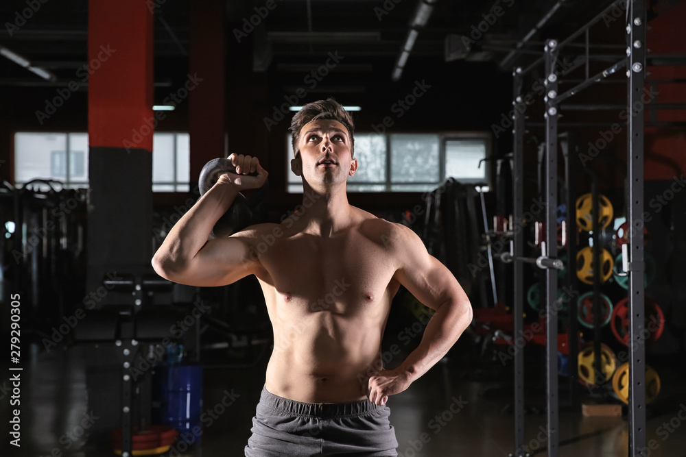 Sporty young man training with kettlebell in gym