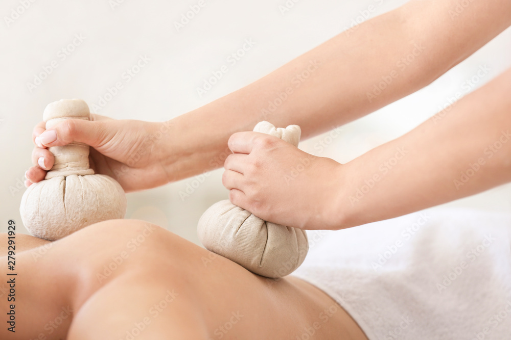 Young woman having massage with herbal bags in spa salon Young woman having massage with herbal bags in spa salon