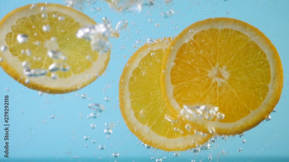 Sliced Orange Plunging and Splashes in Water at Blue Background Sliced Orange Plunging and Splashes in Water at Blue Background