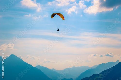 Paragliders flying over mountains in Interlaken, Switzerland. Silhouette of Swiss Alps. Tandem paragliding. Dawning, sunset. Extreme sports. Adventure lifestyle. Adrenaline, risk concept
