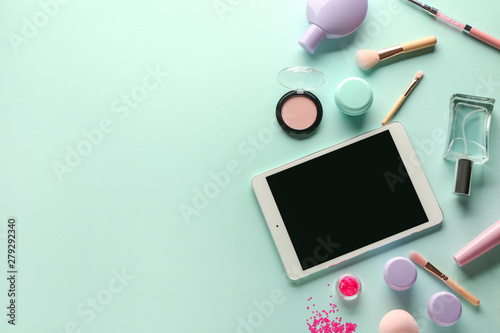Modern tablet computer and cosmetics on color background