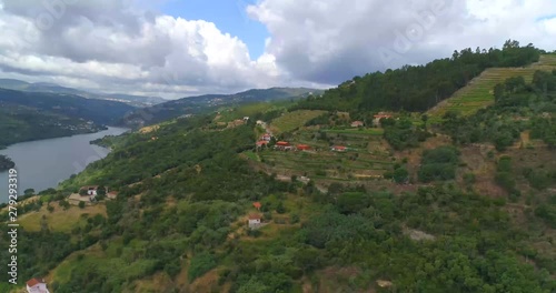 Douro river, aerial, reverse, drone shot, overlooking hills, nature, buildings and vineyard terraces,  the Duero stream, in the background, on a partly sunny day. in Douro, Portinha, Portugal photo