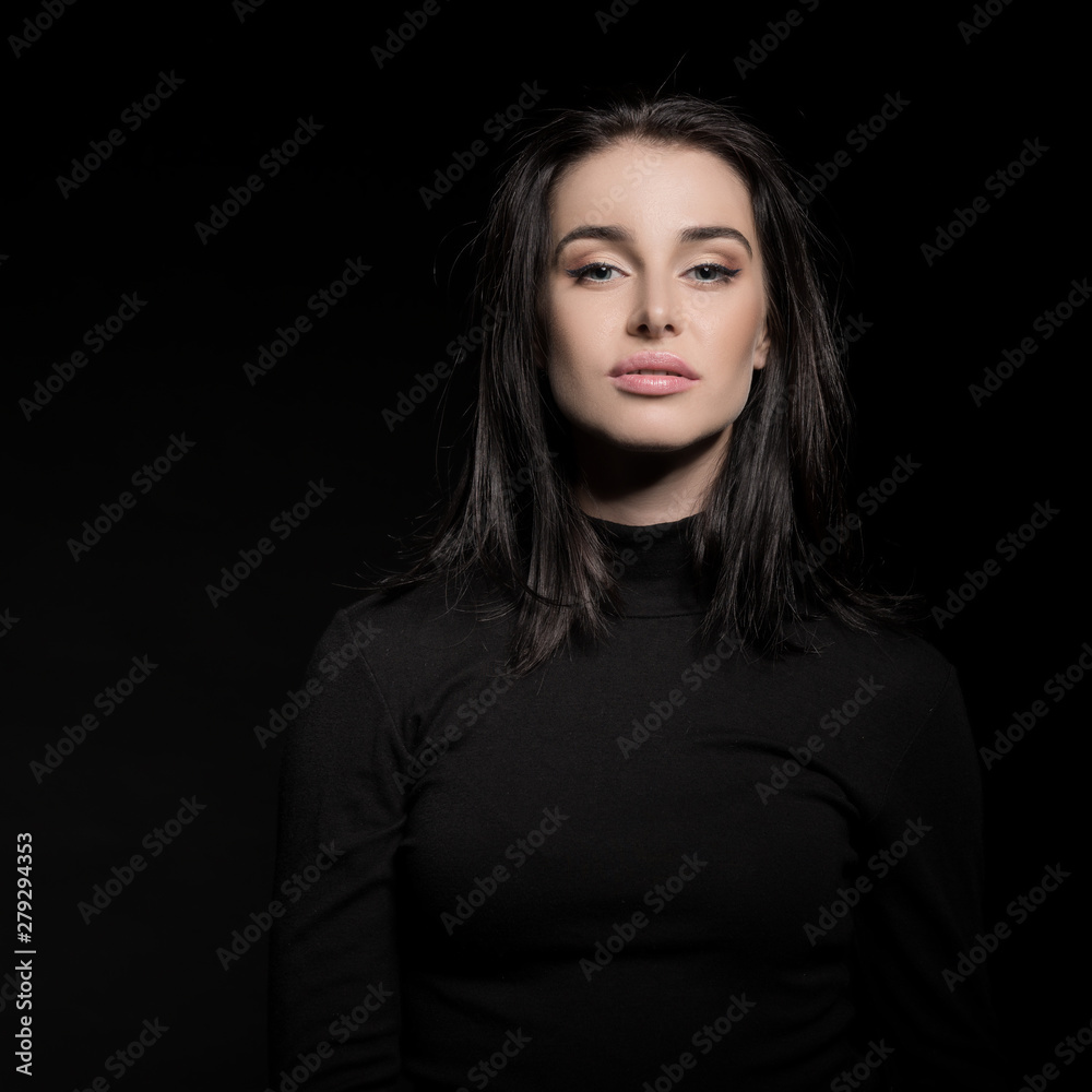Beautiful girl with dark hair posing over black background. Young pretty woman in studio. Beautiful girl with dark hair posing over black background. Young pretty woman in studio.