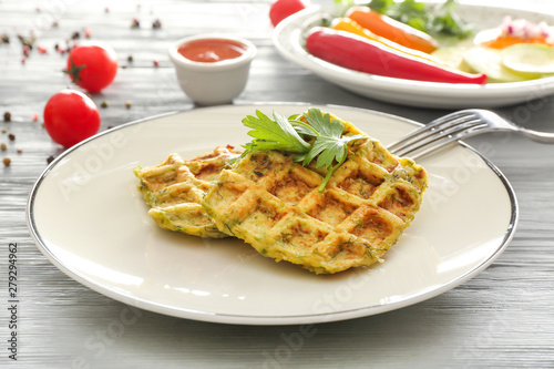 Plate with tasty squash waffles on wooden table