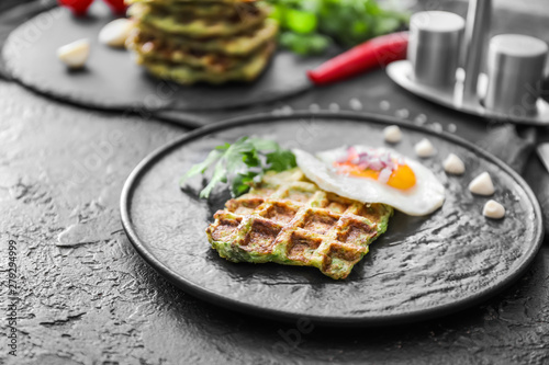 Plate with tasty squash waffle and fried egg on dark table