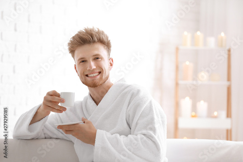 Young man in bathrobe drink...
