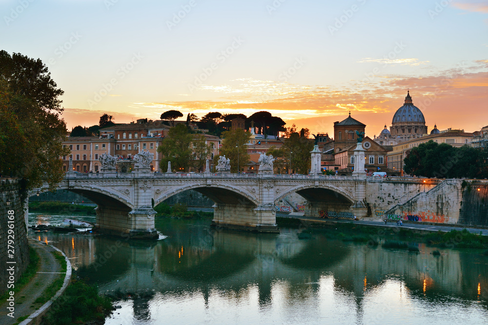 The eternal City. Embankment of the Tiber river and the view of the majestic Rome (Italy) with its bridges and beautiful architecture and Vatican dome of Saint Peter Basilica at sunset.