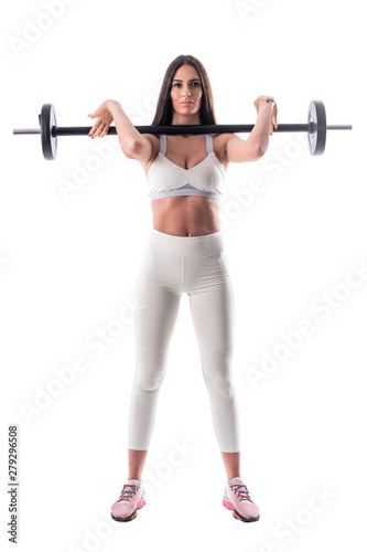 Motivated confident fitness woman holding barbell on her shoulder looking at camera. Full body isolated on white background. 