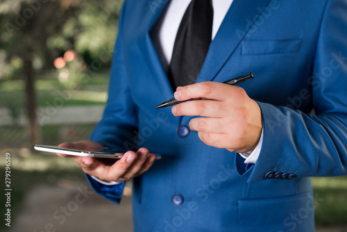 Businessman holds pen and points into copy space. Man with lap top and pen in the hand.
