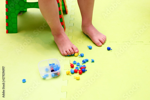 Kids play with mosaic pieces, glass stones. Orthopedic game, gymnastics with valgus, massage and stimulation of the muscles of the feet © misskaterina