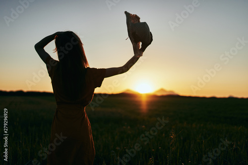 silhouette of woman with arms raised at sunset