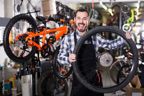 man in apron considering composition of wheel for bicycle