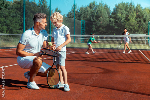 Handsome businessman speaking to son before playing tennis