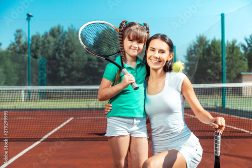 Mommy and daughter holding tennis rackets and smiling