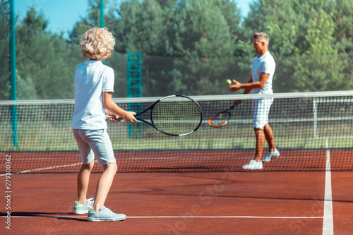 Father and son enjoying warm summer day playing tennis outside © Viacheslav Yakobchuk