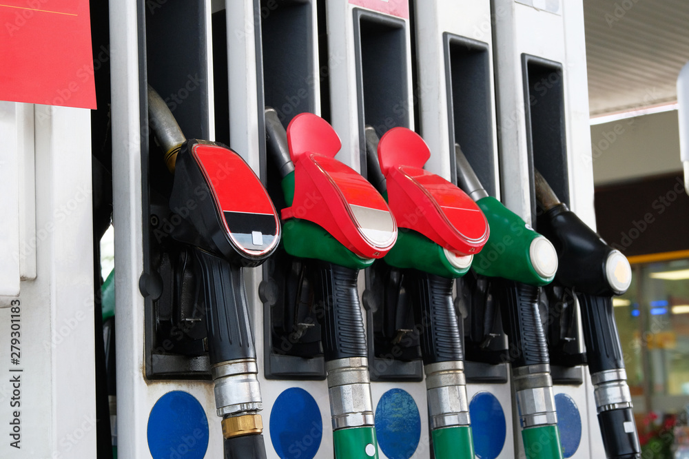 Gasoline and oil products concept. Red and black fuel pistols on fuel station. Pumping petrol at gasoline pump. Close up. Gasoline and oil products concept. Red and black fuel pistols on fuel station. Pumping petrol at gasoline pump. Close up.