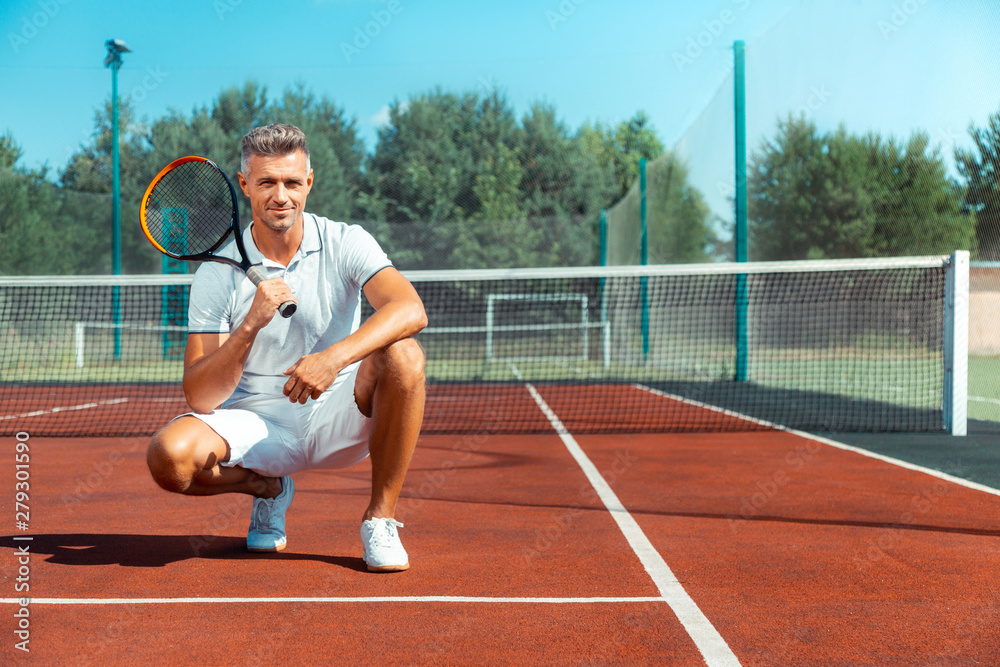 Handsome grey-haired businessman holding tennis racket