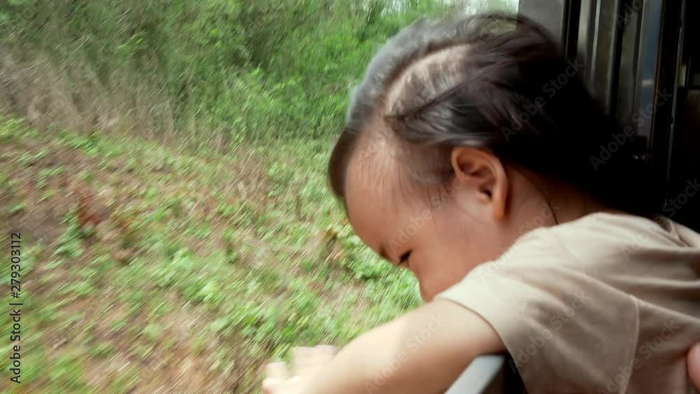 Portrait of Asian child girl stretched out her hand through the window of The vintage diesel engine train to touch the wind while travel to Lampang province, Thailand with her family. Portrait of Asian child girl stretched out her hand through the window of The vintage diesel engine train to touch the wind while travel to Lampang province, Thailand with her family.
