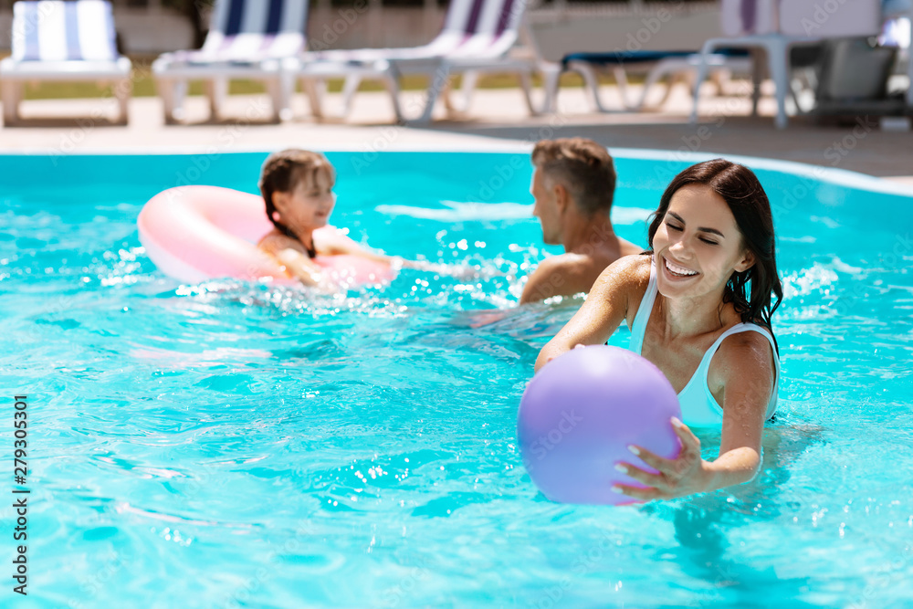 Mom catching the ball in pool while having fun together Mom catching the ball in pool while having fun together