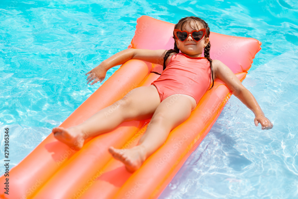 Funny girl wearing sunglasses chilling on air mattress in the pool