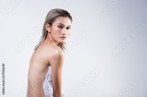 Beautiful Asian Woman bronze hair holding transparent fabric and sit on stool to show back skin are  studio lighting off white background isolated