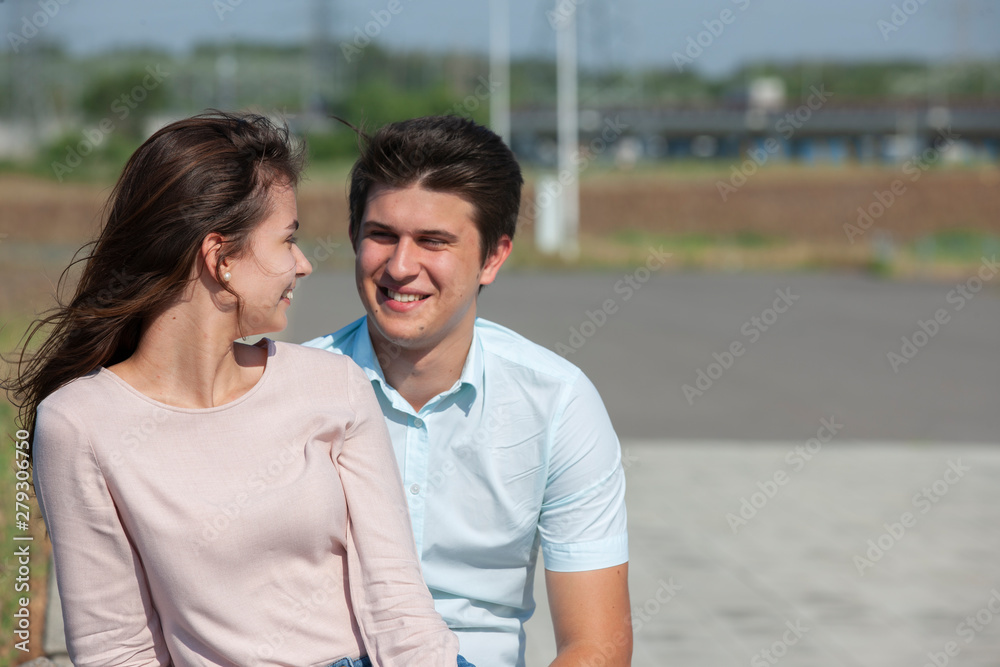 Obraz premium beautiful young couple sitting on a bench in the park