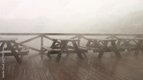 Empty benches in a garden restaurant during extreme cloud-burst photo