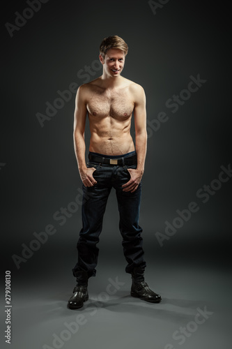 Full length portrait of a sexy young man in jeans and shirtless posing at studio.