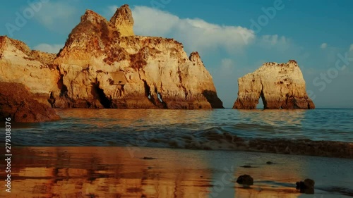 Beautiful sunset slow motion of pristine waters and beautiful rock formations in Tres Irmaos Beach in Alvor, The Algarve, Portugal photo