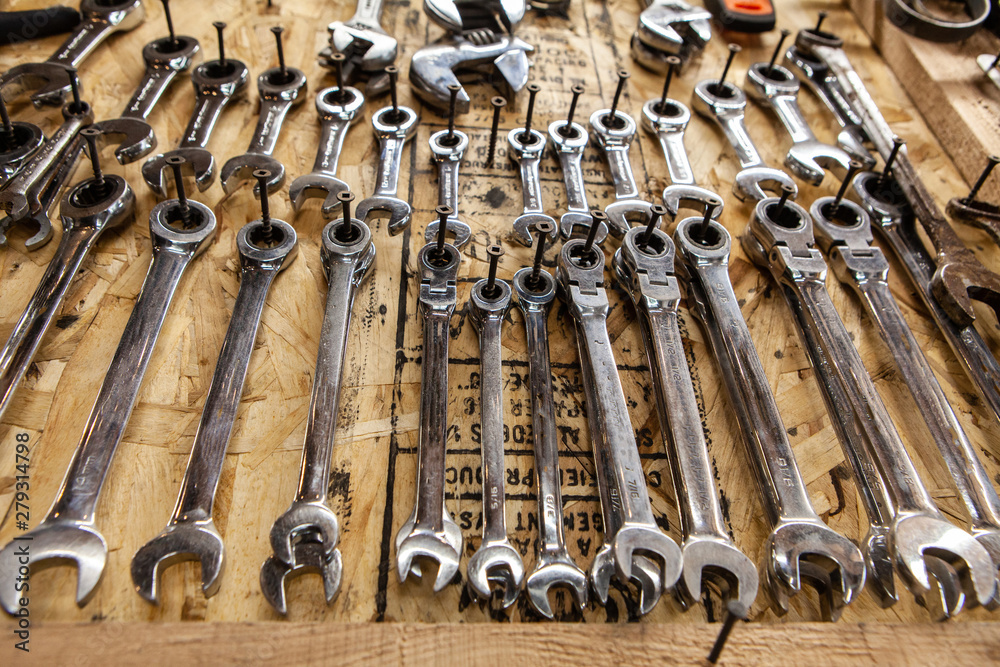 Spanners hanging inside a workshop. A low angle and closeup view on a selection of metal wrenches inside a garage. Hanging on screws in varying sizes. for easy access. Spanners hanging inside a workshop. A low angle and closeup view on a selection of metal wrenches inside a garage. Hanging on screws in varying sizes. for easy access.