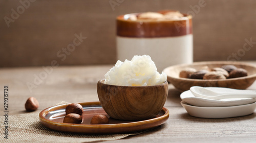 Shea butter in wooden bowl with nuts . Free text space.