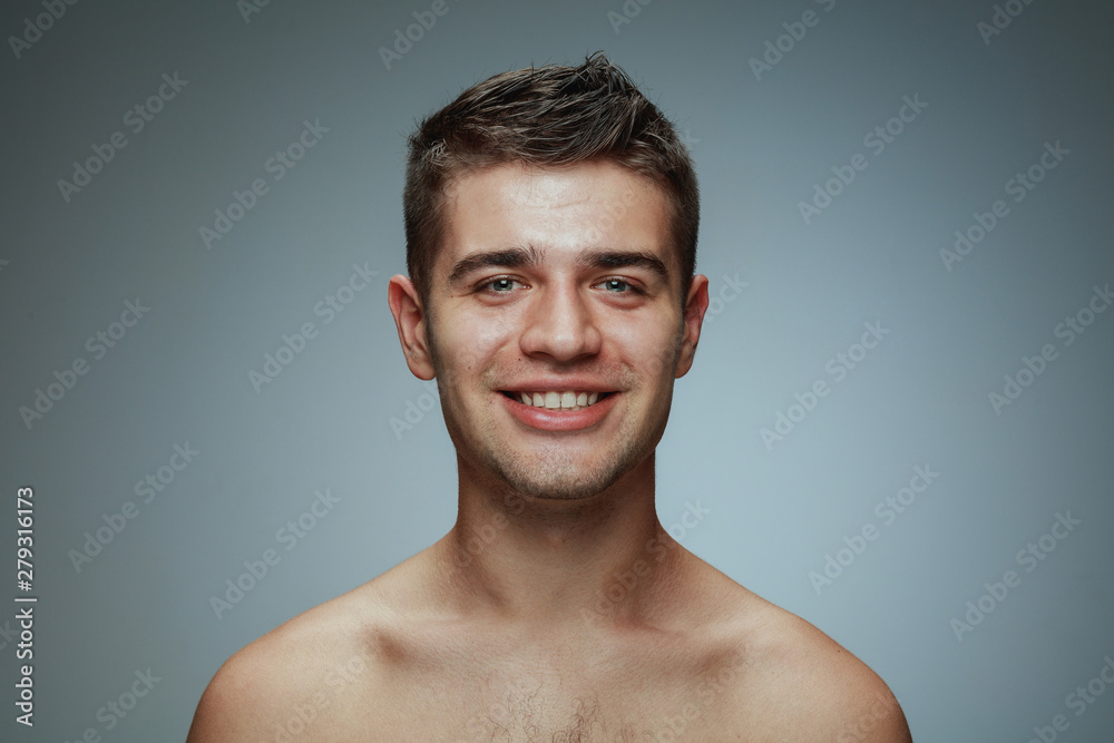 Portrait of shirtless young man isolated on grey studio background. Caucasian healthy male model looking at camera, smiling and posing. Concept of men's health and beauty, self-care, body and skin Portrait of shirtless young man isolated on grey studio background. Caucasian healthy male model looking at camera, smiling and posing. Concept of men's health and beauty, self-care, body and skin