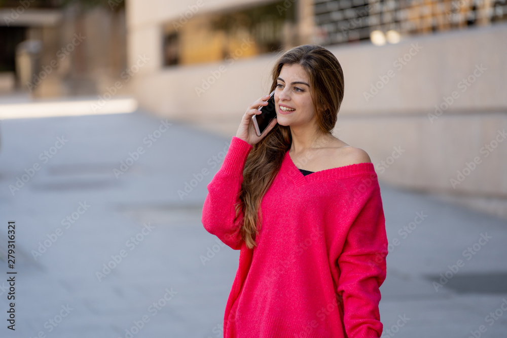 Attractive young student woman talking and chatting on her smart phone outside in an European city
