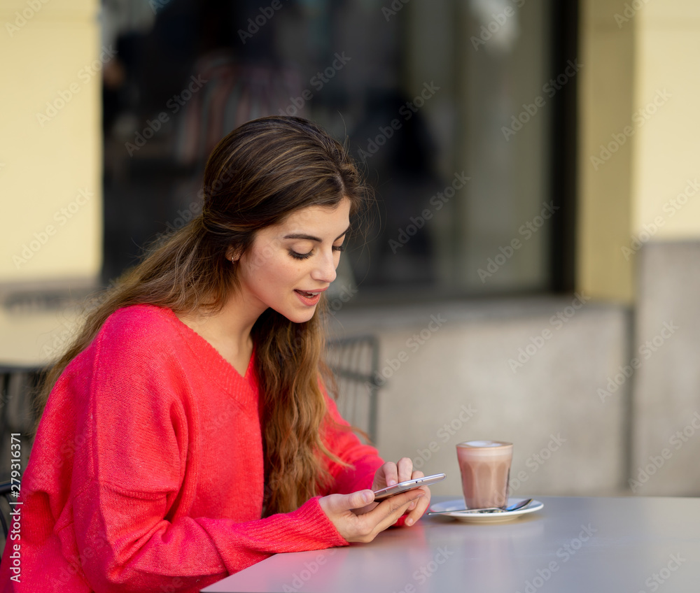 Attractive young woman using smart mobile phone app in a coffee shop terrace Attractive young woman using smart mobile phone app in a coffee shop terrace