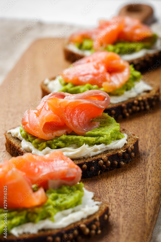 open sandwich with avocado and salmon on wood board