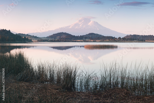 A reflection of snow capped Mount Shasta in a clear water in lake at sunrise in California State, USA. Mount Shasta is a volcano at the southern end of the Cascade Range in Siskiyou County 