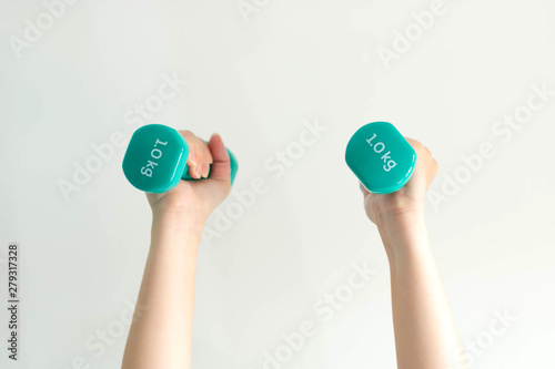 Close-up image of two hands lifting dumbbells overhead on white background.